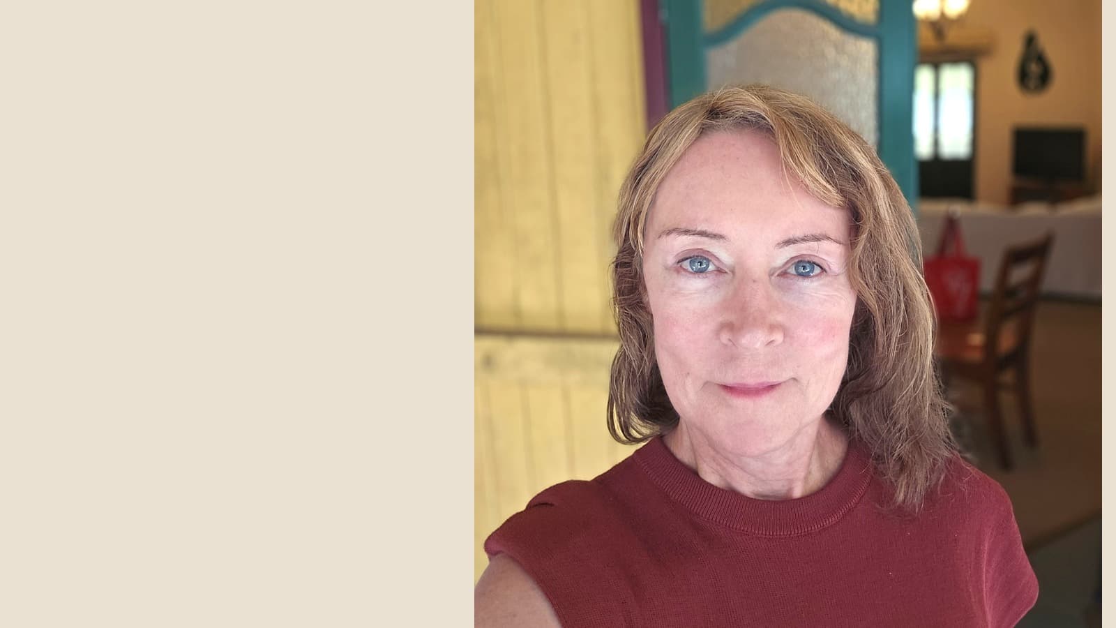 A woman with blue eyes and light brown hair wearing a maroon top, looking forward.