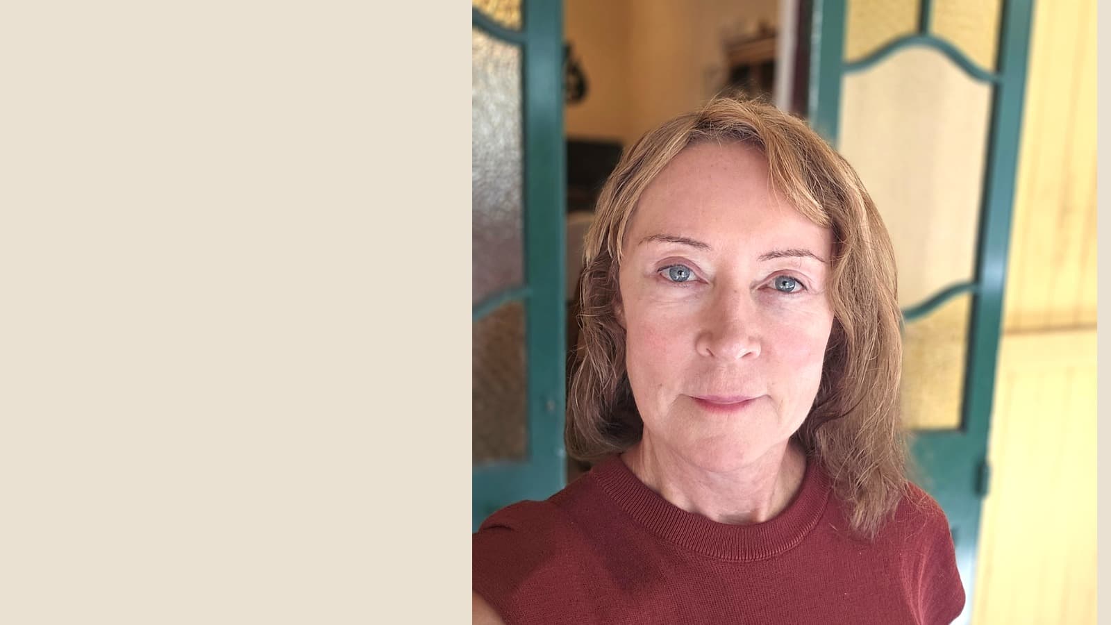 Middle-aged woman with light brown hair and blue eyes wearing a reddish-brown top.